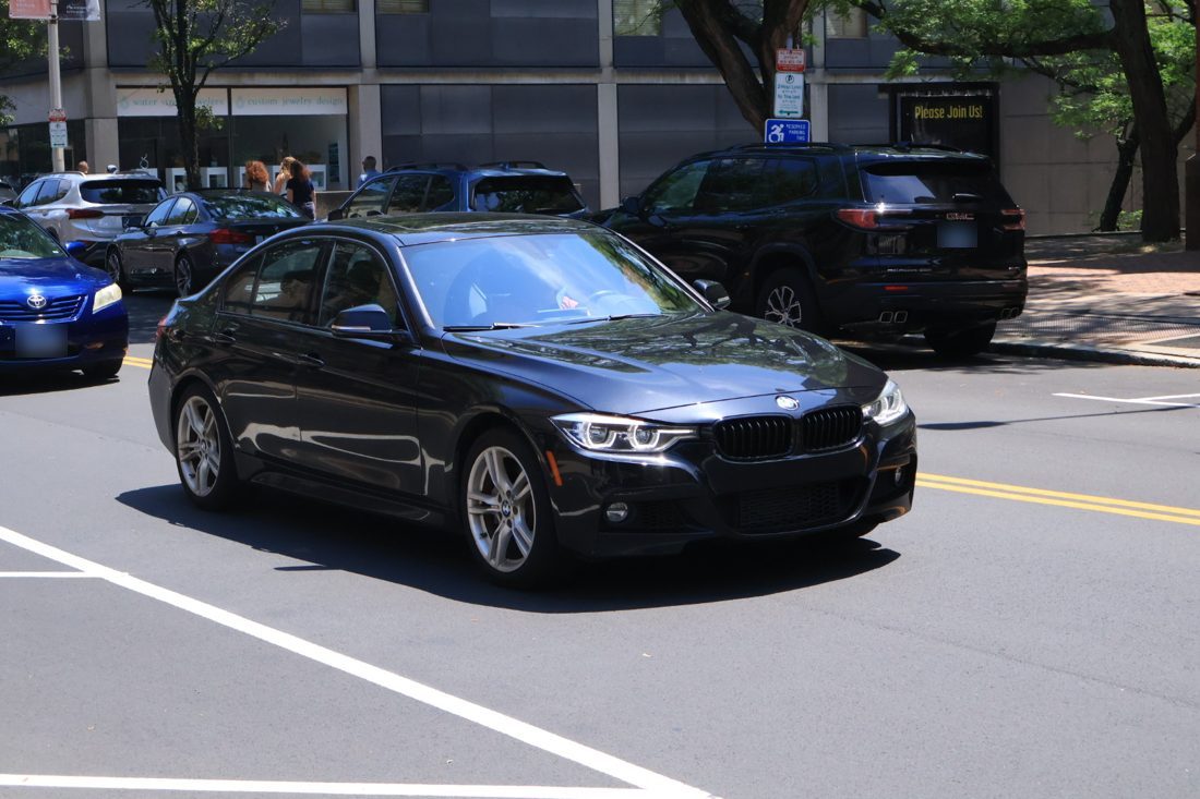 A black sedan turning on a sunny downtown street